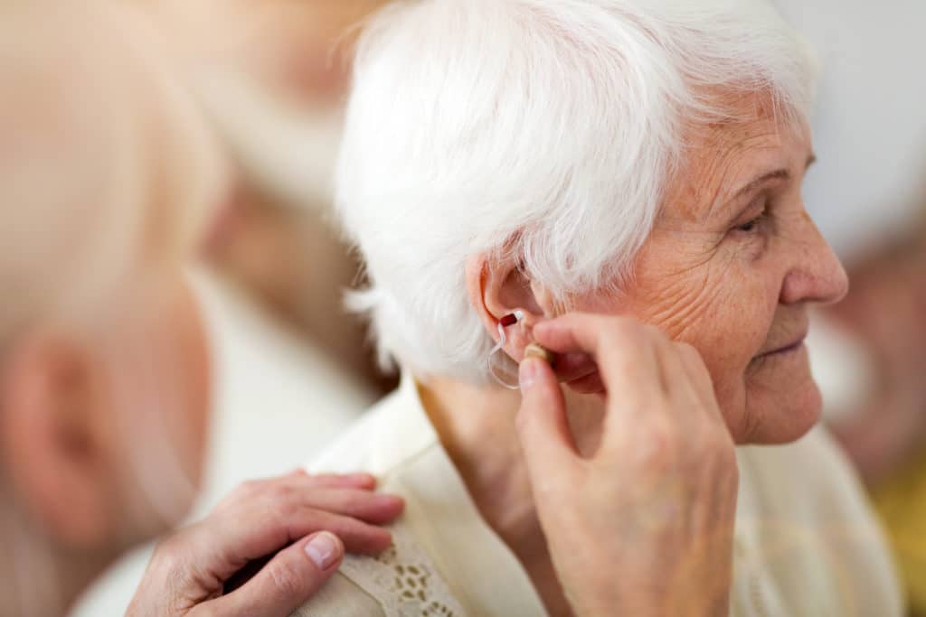Femme qui se fait poser un appareil auditif dans l'oreille droite grâce à l'offre 100% santé